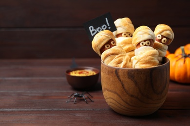 Photo of Spooky sausage mummies for Halloween party served on wooden table, space for text