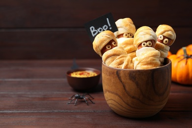 Spooky sausage mummies for Halloween party served on wooden table, space for text