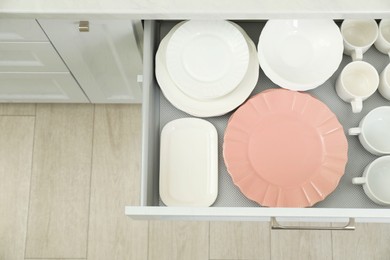 Clean plates, bowls and cups in drawer indoors, top view