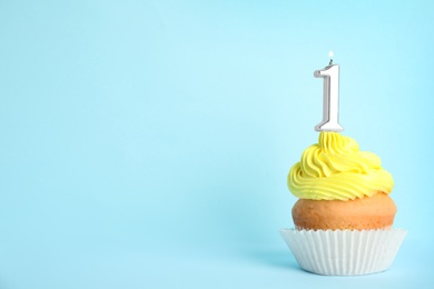 Birthday cupcake with number one candle on blue background, space for text