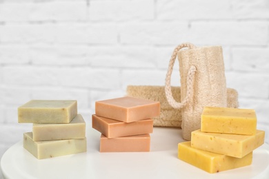 Photo of Stacks of handmade soap bars and sponges on table against white background