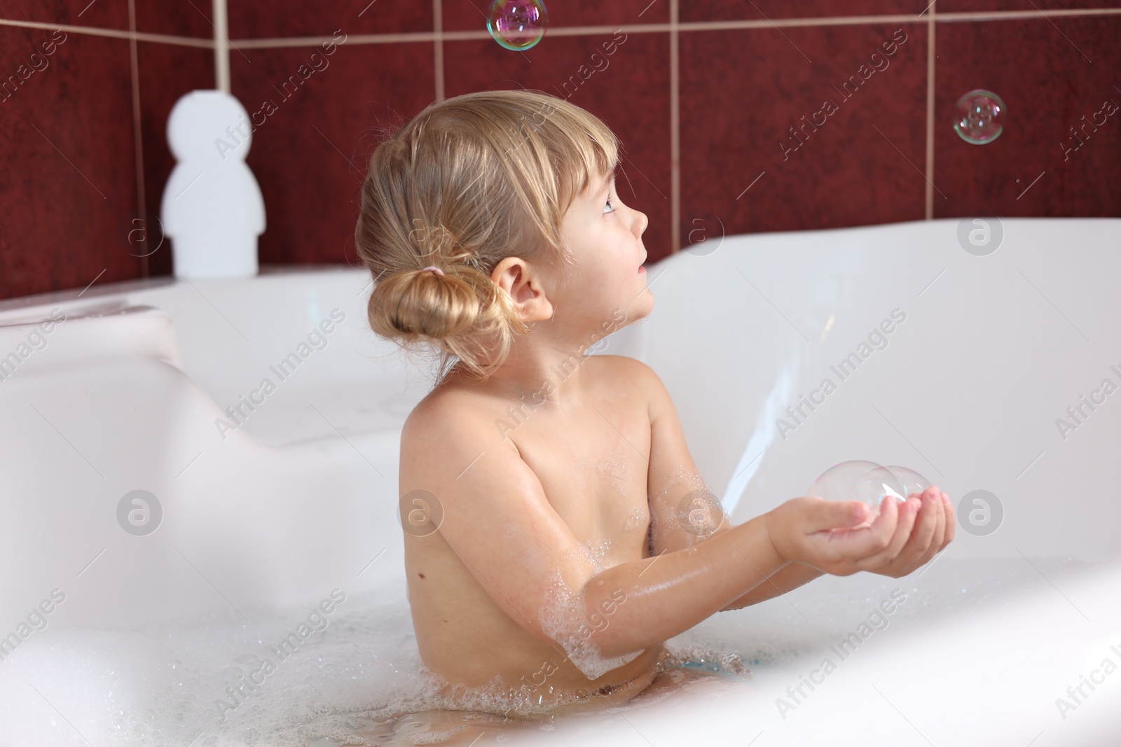 Photo of Little girl having fun in bathtub at home