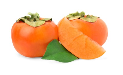 Whole and cut delicious ripe juicy persimmons with green leaf on white background