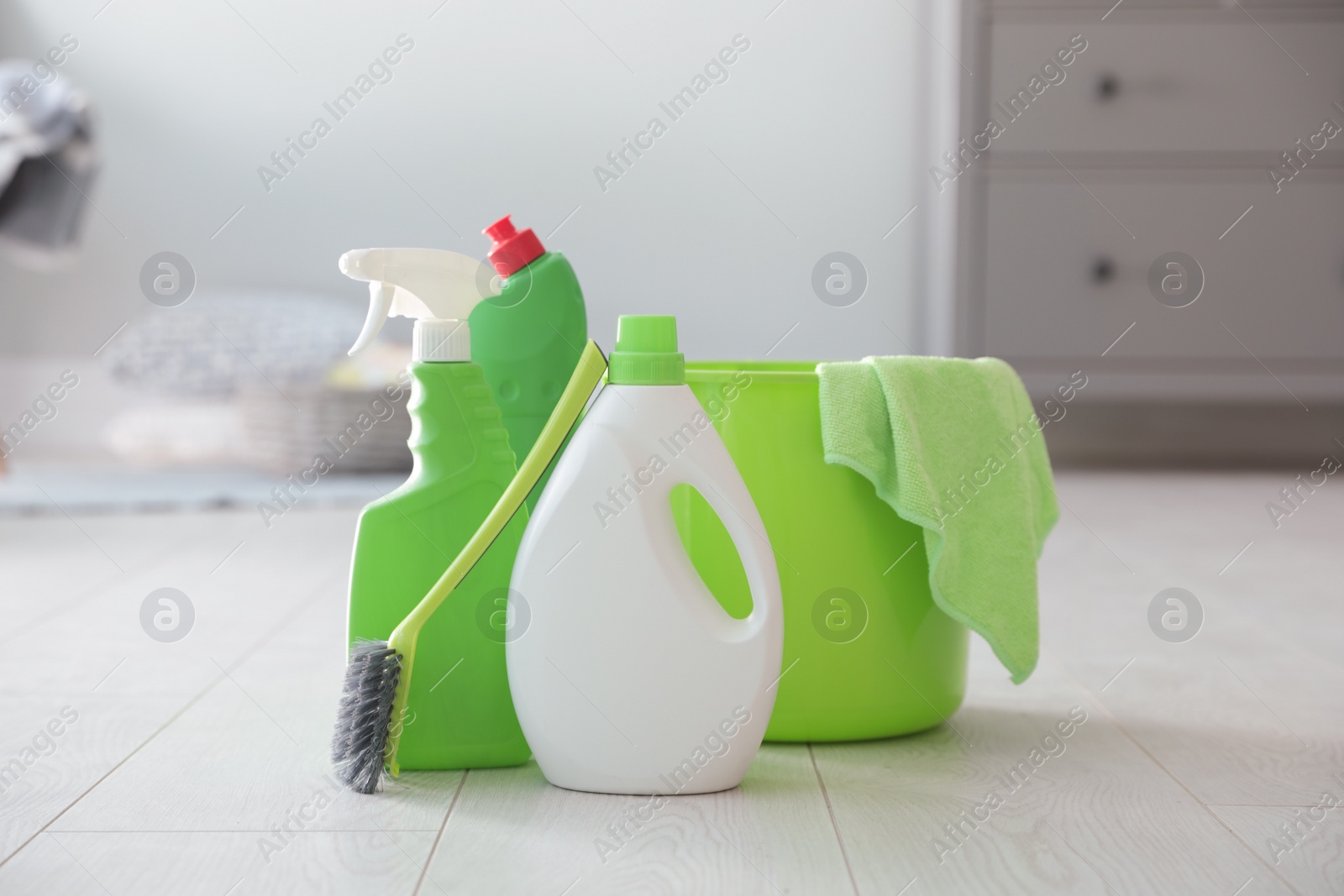 Photo of Bucket with cleaning products and supplies on floor indoors