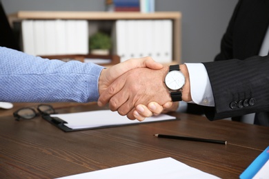 Photo of Lawyer shaking hands with client in office, closeup