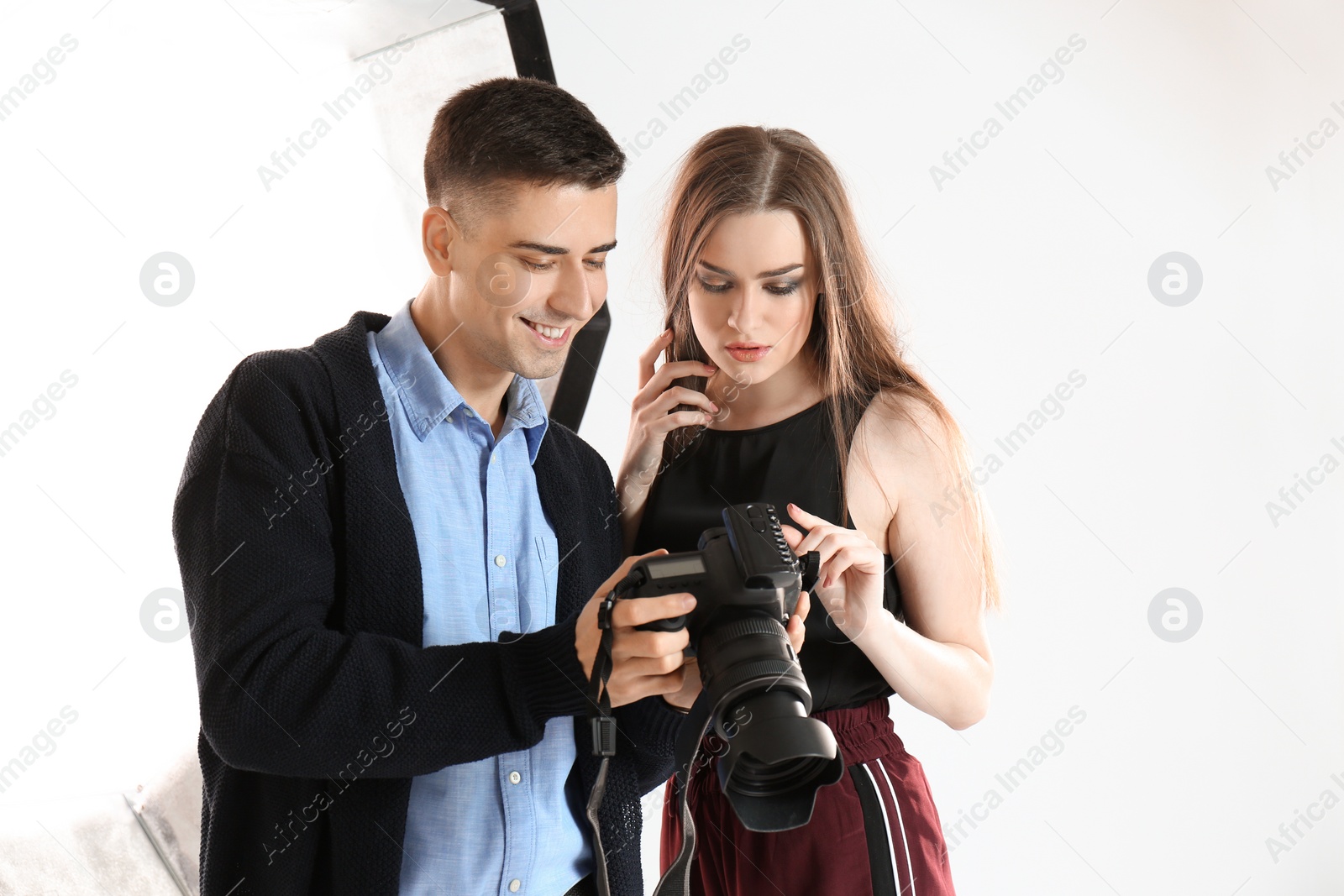 Photo of Photographer showing model her photos in professional studio