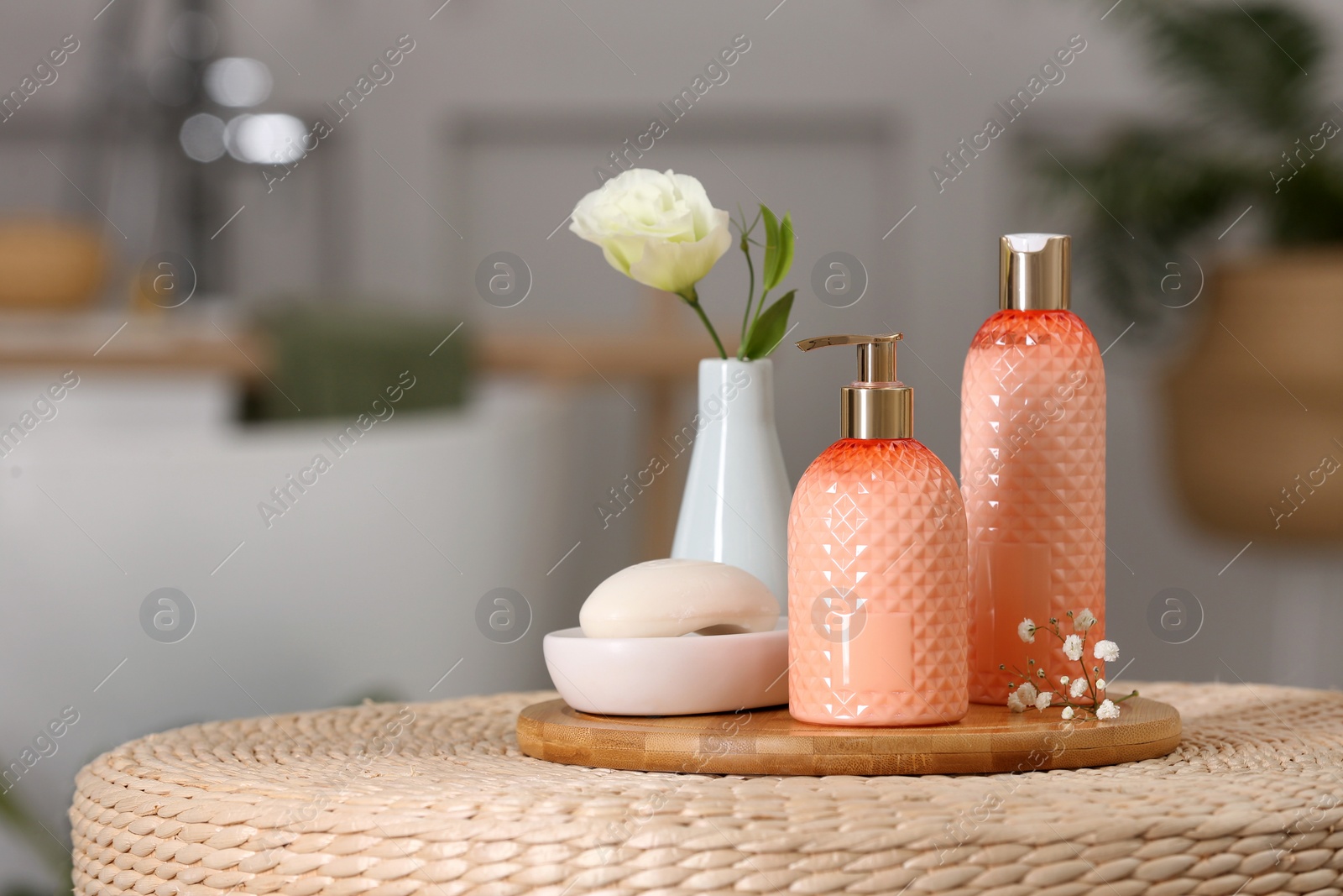 Photo of Liquid soap and other toiletries on wicker stand in bathroom