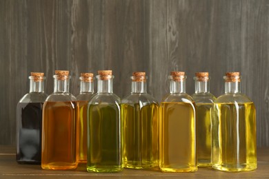 Photo of Vegetable fats. Different oils in glass bottles on wooden table