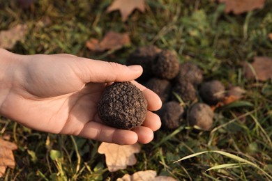 Woman holding fresh truffle in hand outdoors, closeup