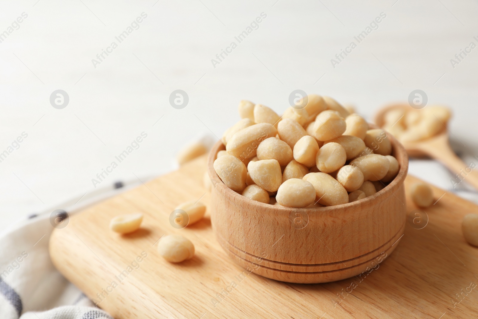 Photo of Shelled peanuts in wooden bowl on board