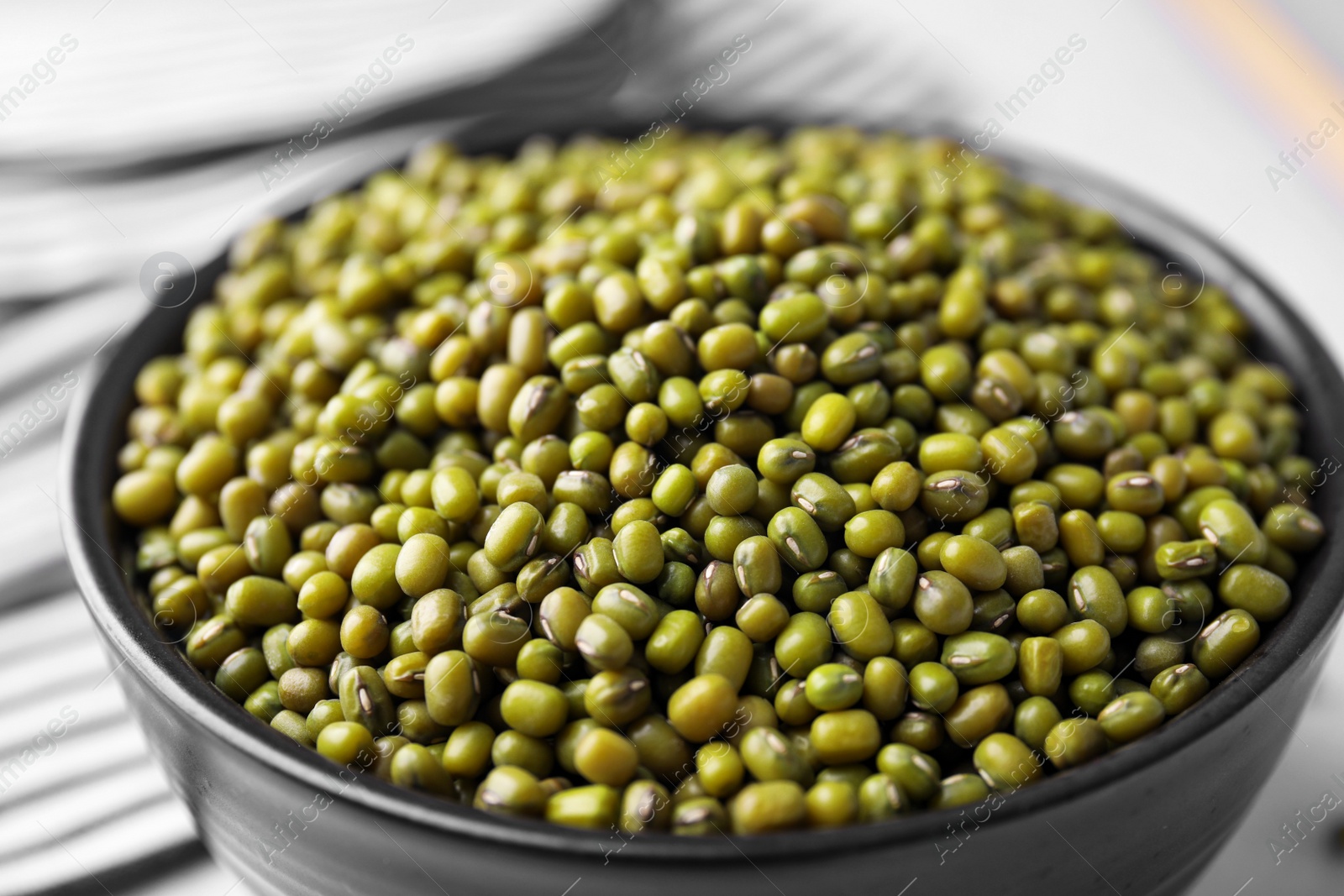 Photo of Bowl with green mung beans on table, closeup