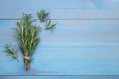 Photo of Bunch of rosemary on light blue wooden table, top view. Space for text