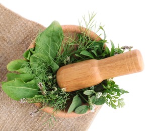 Wooden mortar, pestle and different herbs on cloth against white background, top view