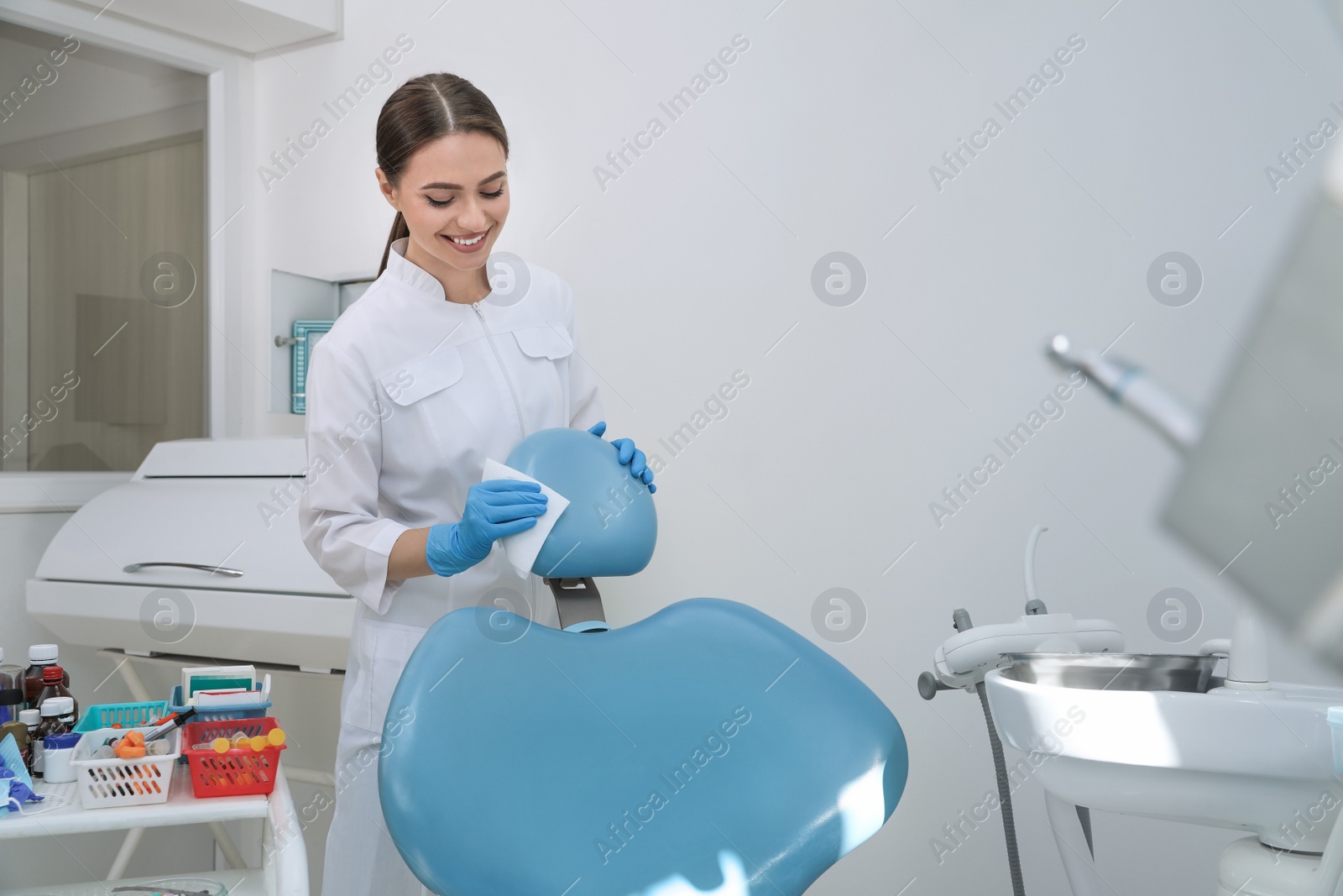 Photo of Professional dentist in white coat cleaning workplace  indoors