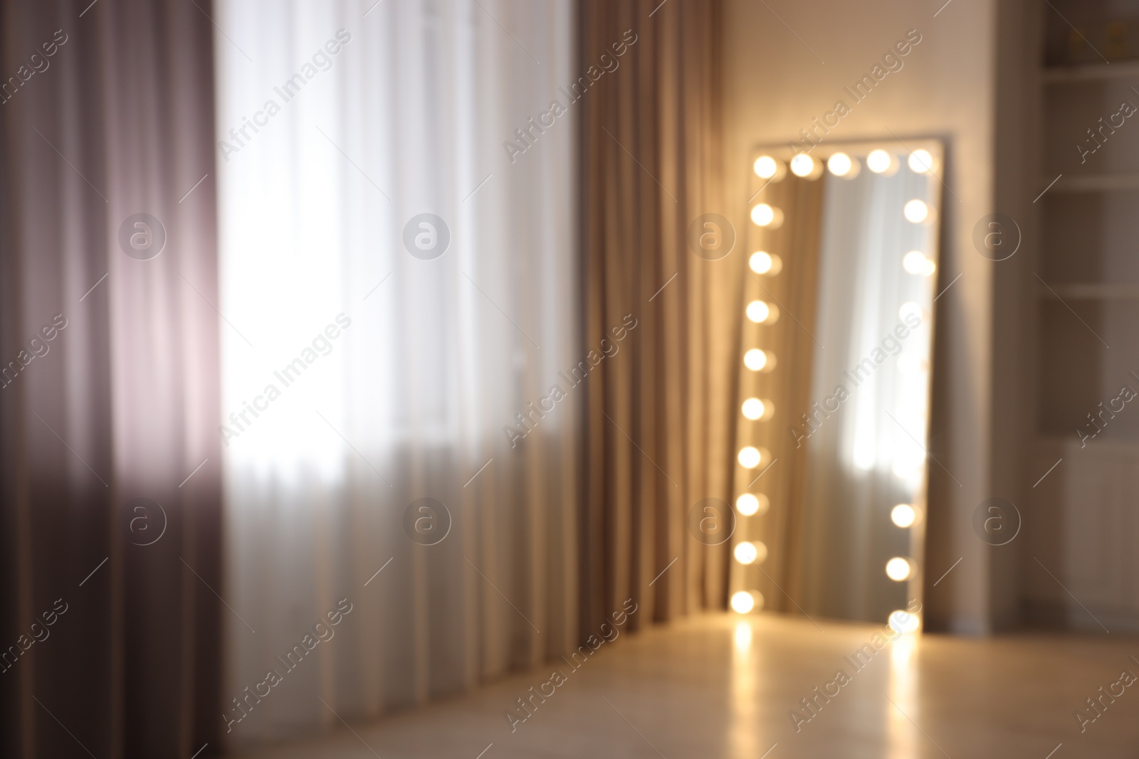 Photo of Modern mirror with light bulbs in makeup room, blurred view