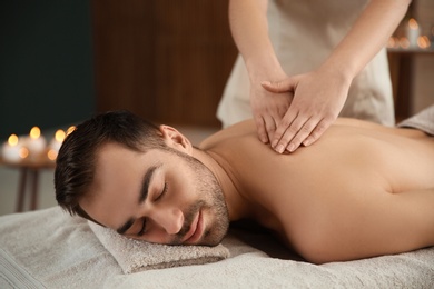 Photo of Handsome man receiving back massage in spa salon