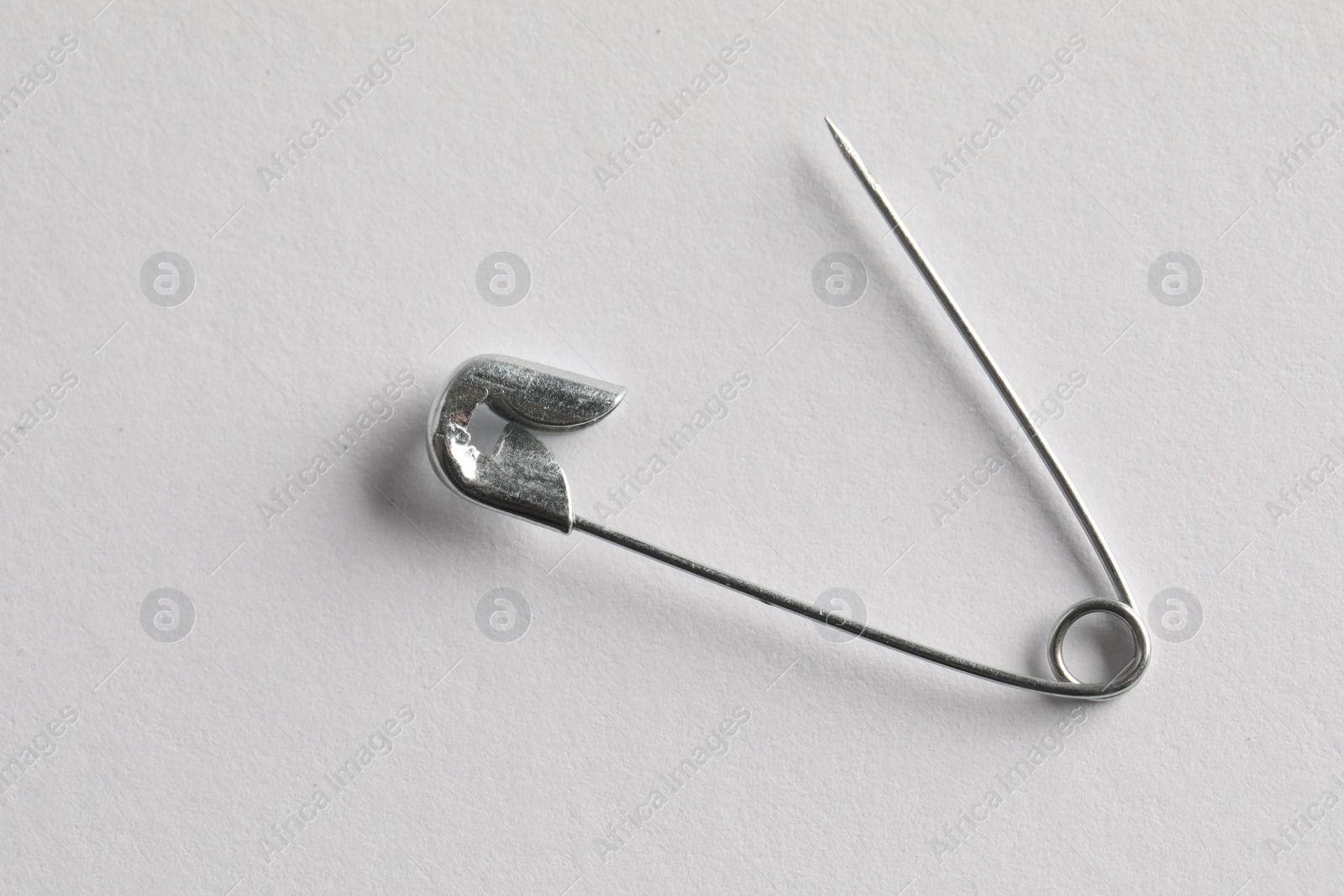 Photo of Metal safety pin on white background, top view