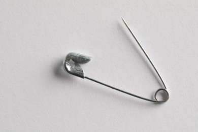 Metal safety pin on white background, top view