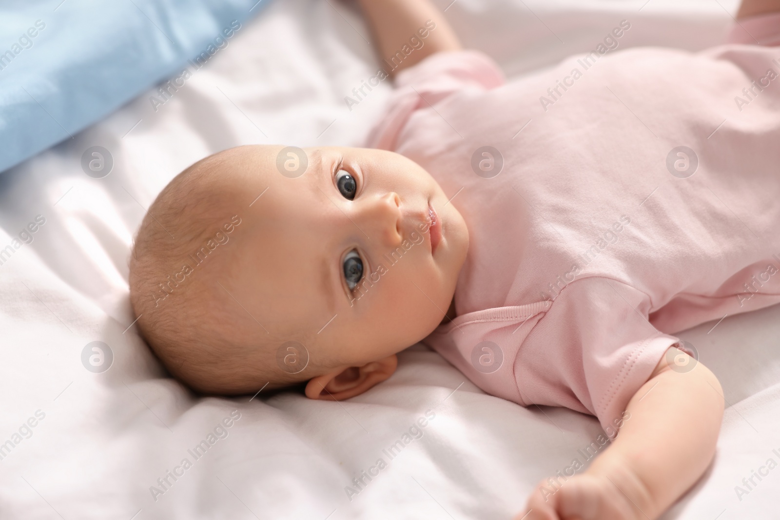 Photo of Cute little baby lying on white sheets