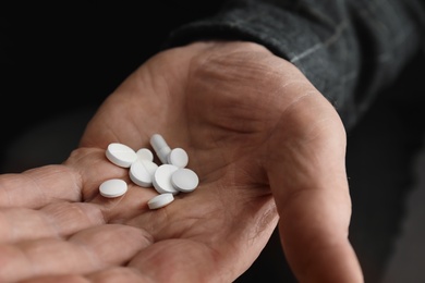Photo of Senior man holding pills in his hand, closeup