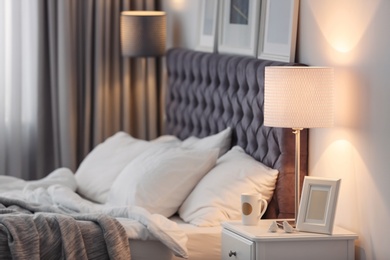 Photo of Modern room interior with comfortable bed and stylish lamp