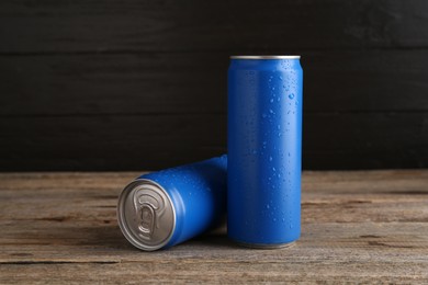 Photo of Energy drinks in wet cans on wooden table