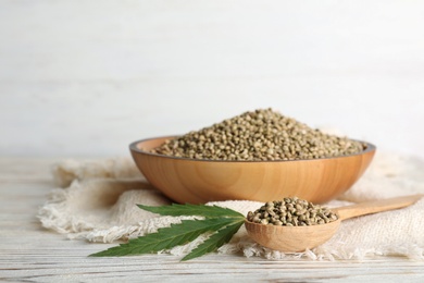 Photo of Spoon and bowl with hemp seeds on table