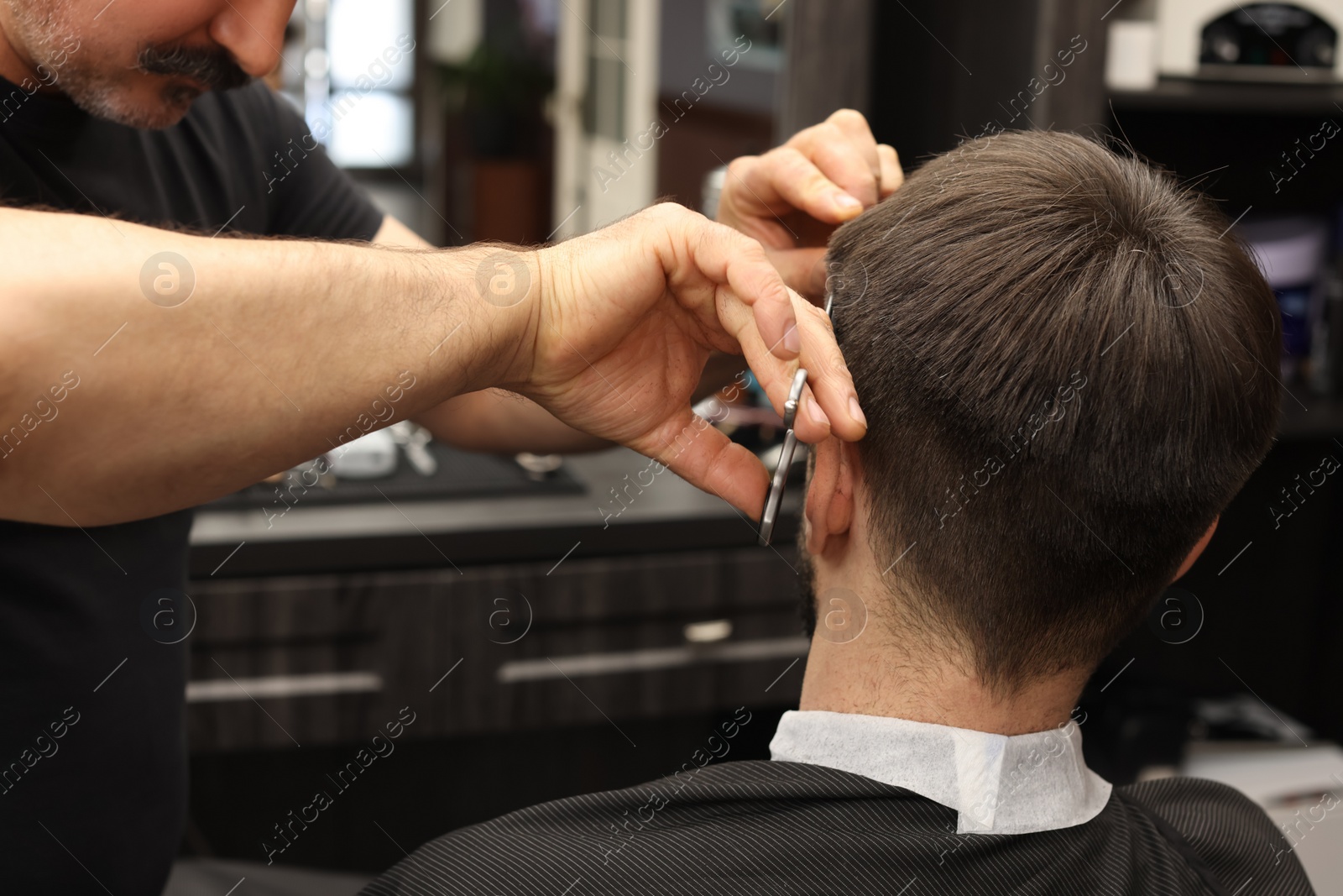 Photo of Professional hairdresser cutting man's hair in barbershop