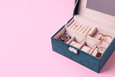 Jewelry box with many different accessories on pink background. Space for text