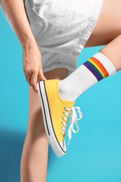 Photo of Woman posing in yellow classic old school sneakers on light blue background, closeup