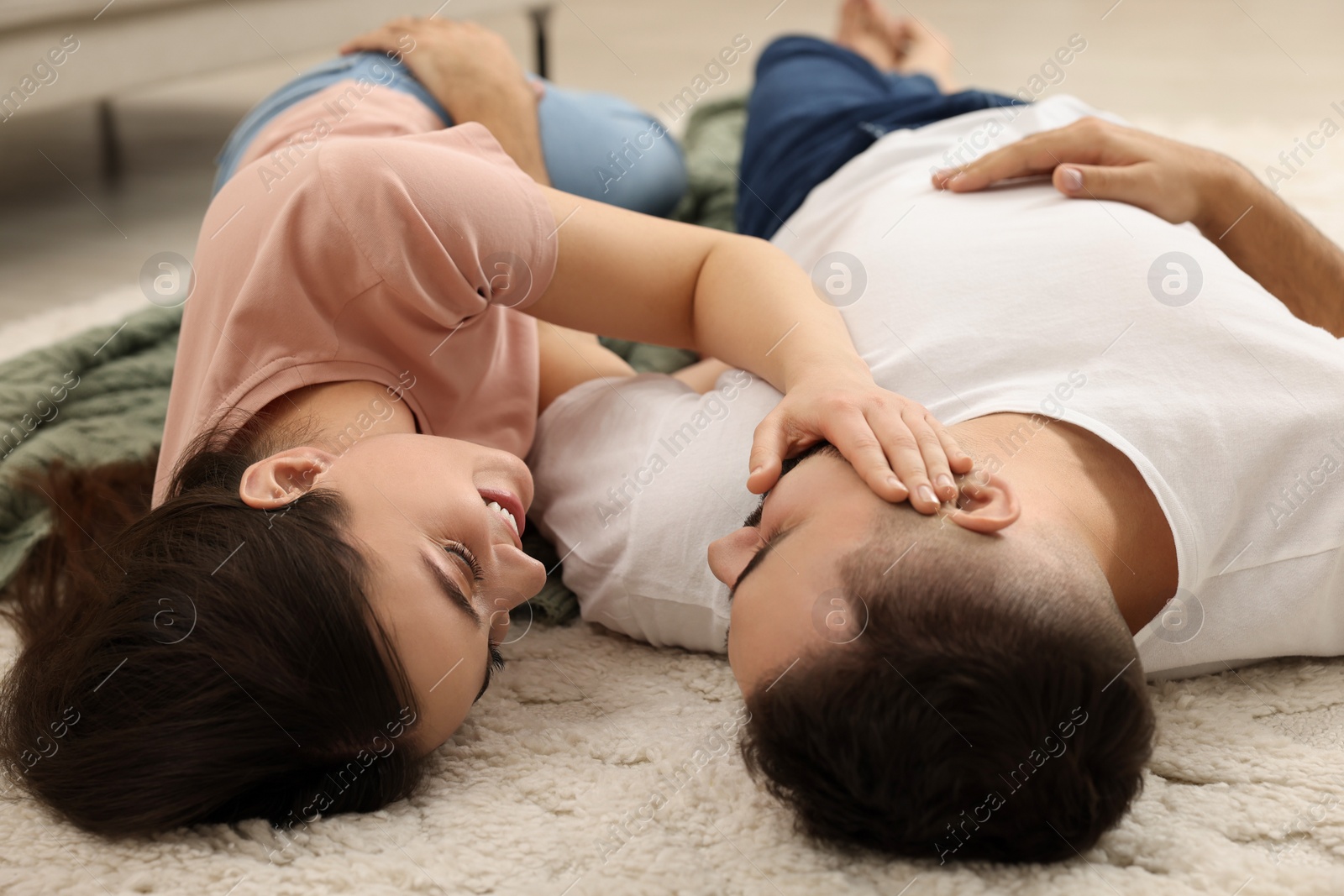 Photo of Affectionate young couple spending time together on soft carpet at home