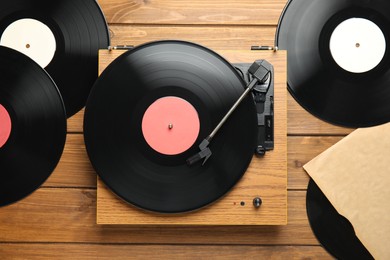 Photo of Vintage vinyl records and turntable on wooden background, flat lay
