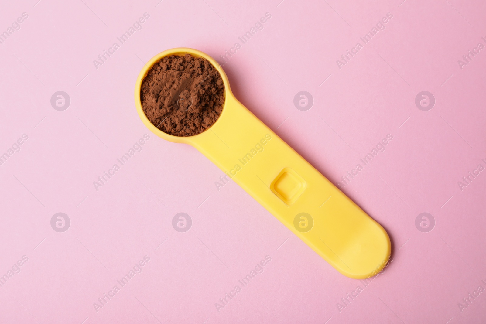 Photo of Spoon of protein powder on pink background, top view