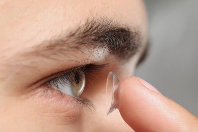 Photo of Closeup view of young man putting in contact lens