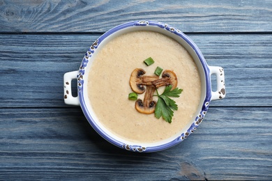 Bowl of fresh homemade mushroom soup on wooden background, top view