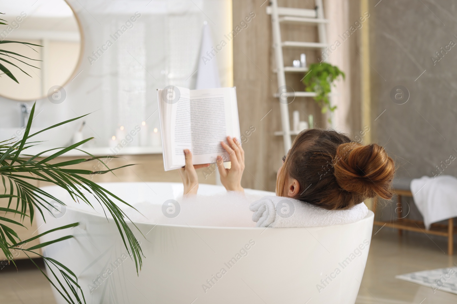 Photo of Woman reading book while enjoying bubble bath at home
