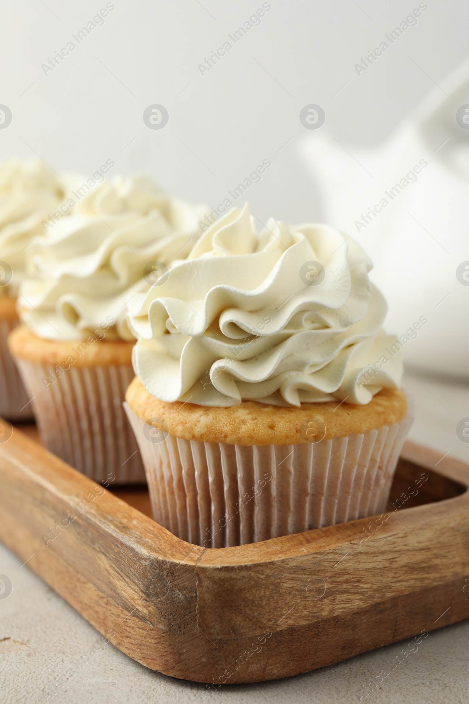 Photo of Tasty cupcakes with vanilla cream on light grey table, closeup