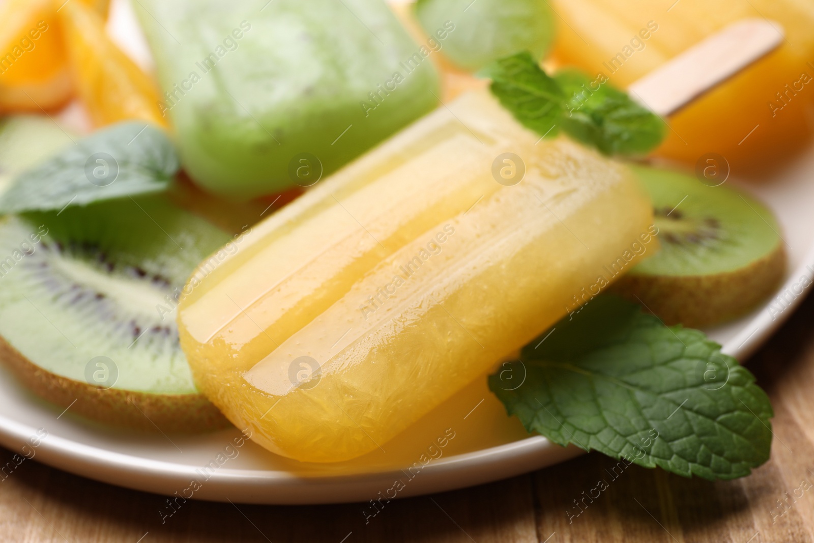 Photo of Plate of tasty orange and kiwi ice pops on table, closeup. Fruit popsicle