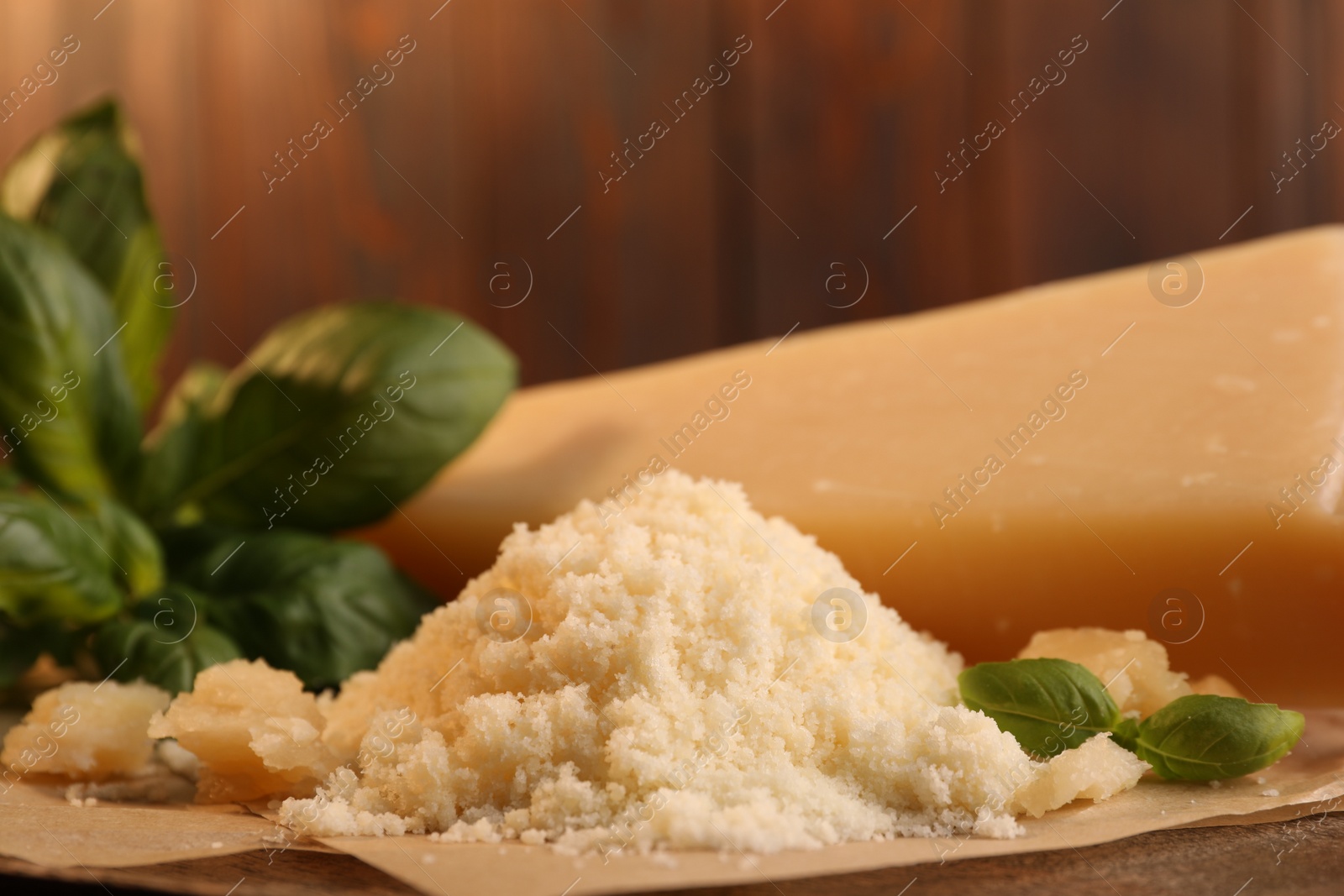 Photo of Delicious grated parmesan cheese and basil on parchment paper, closeup