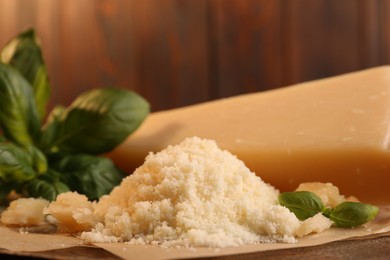Photo of Delicious grated parmesan cheese and basil on parchment paper, closeup