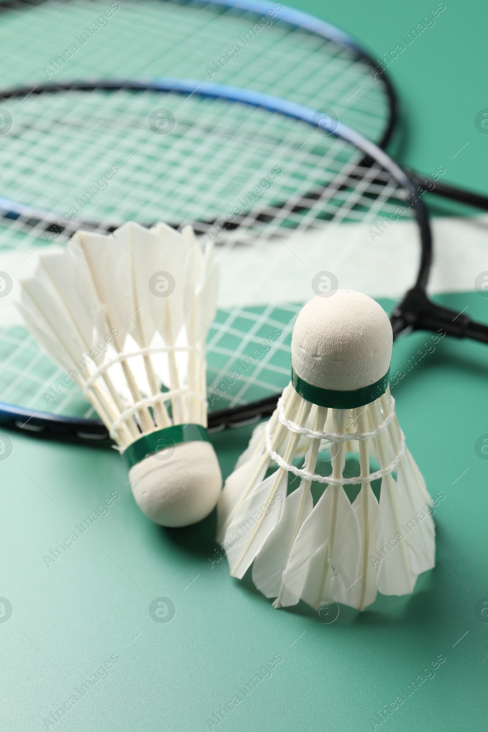 Photo of Feather badminton shuttlecocks and rackets on green table, closeup