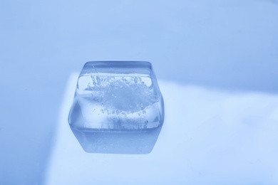 Photo of Ice cube on color mirror surface. Space for text