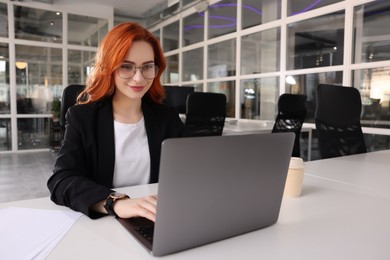 Woman working with laptop at white desk in office