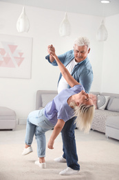 Photo of Happy mature couple dancing together in living room