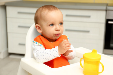 Photo of Cute little baby in highchair at home