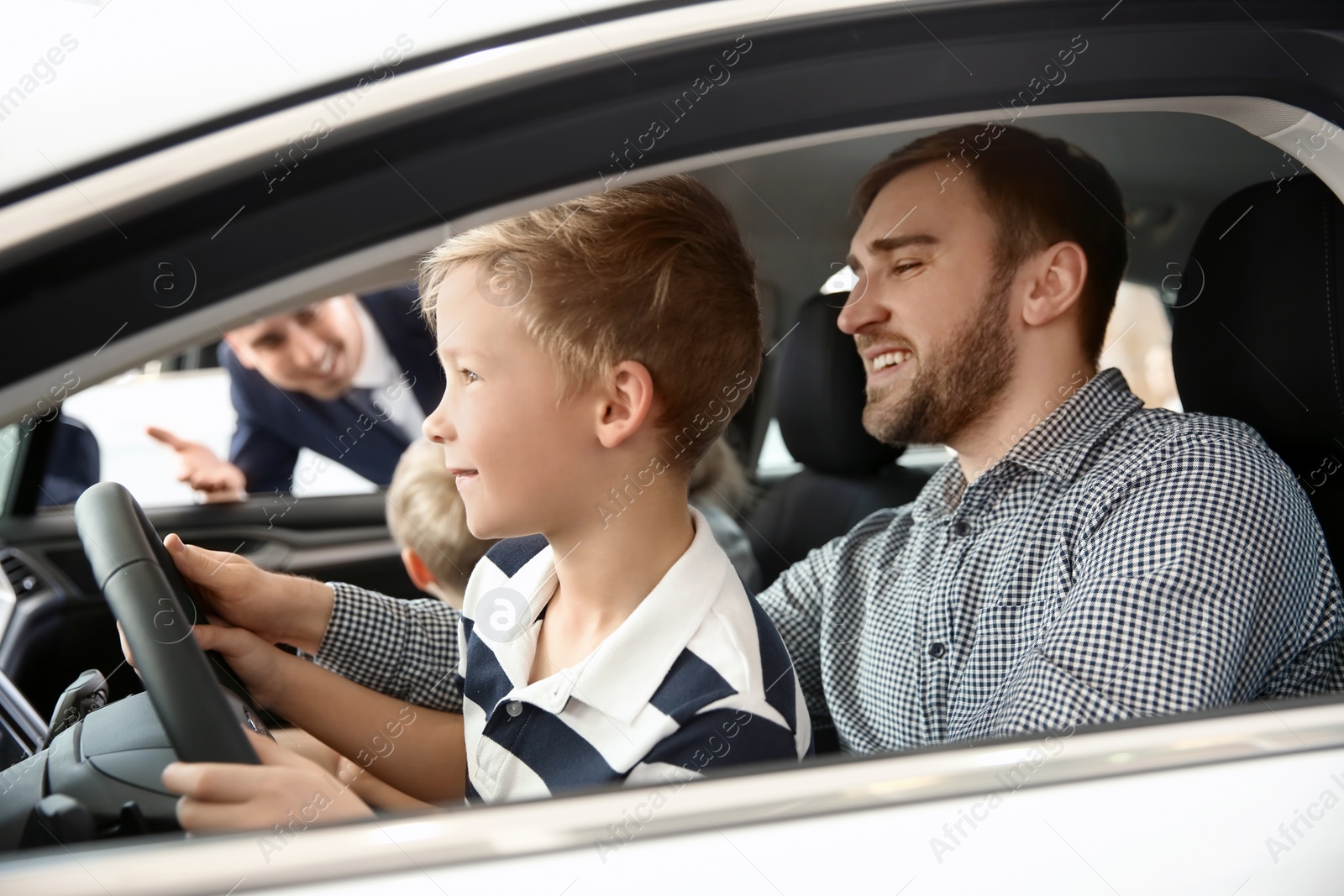 Photo of Young family choosing new car with salesman in salon