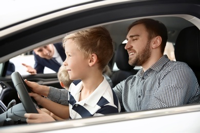 Young family choosing new car with salesman in salon