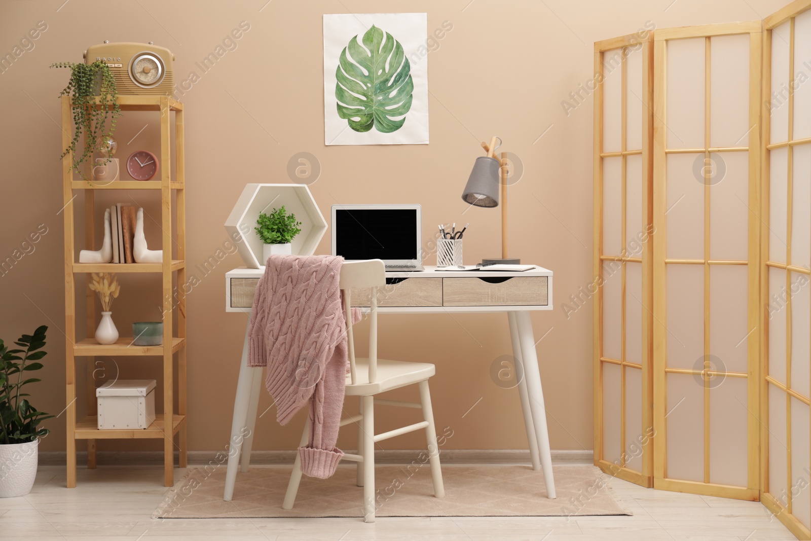 Photo of Cozy workplace with modern laptop on desk and comfortable chair at home