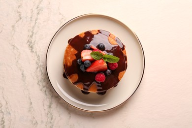 Stack of tasty pancakes with fresh berries, chocolate sauce and mint on white table, top view