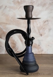 Photo of Beautiful traditional hookah on wooden table against light background